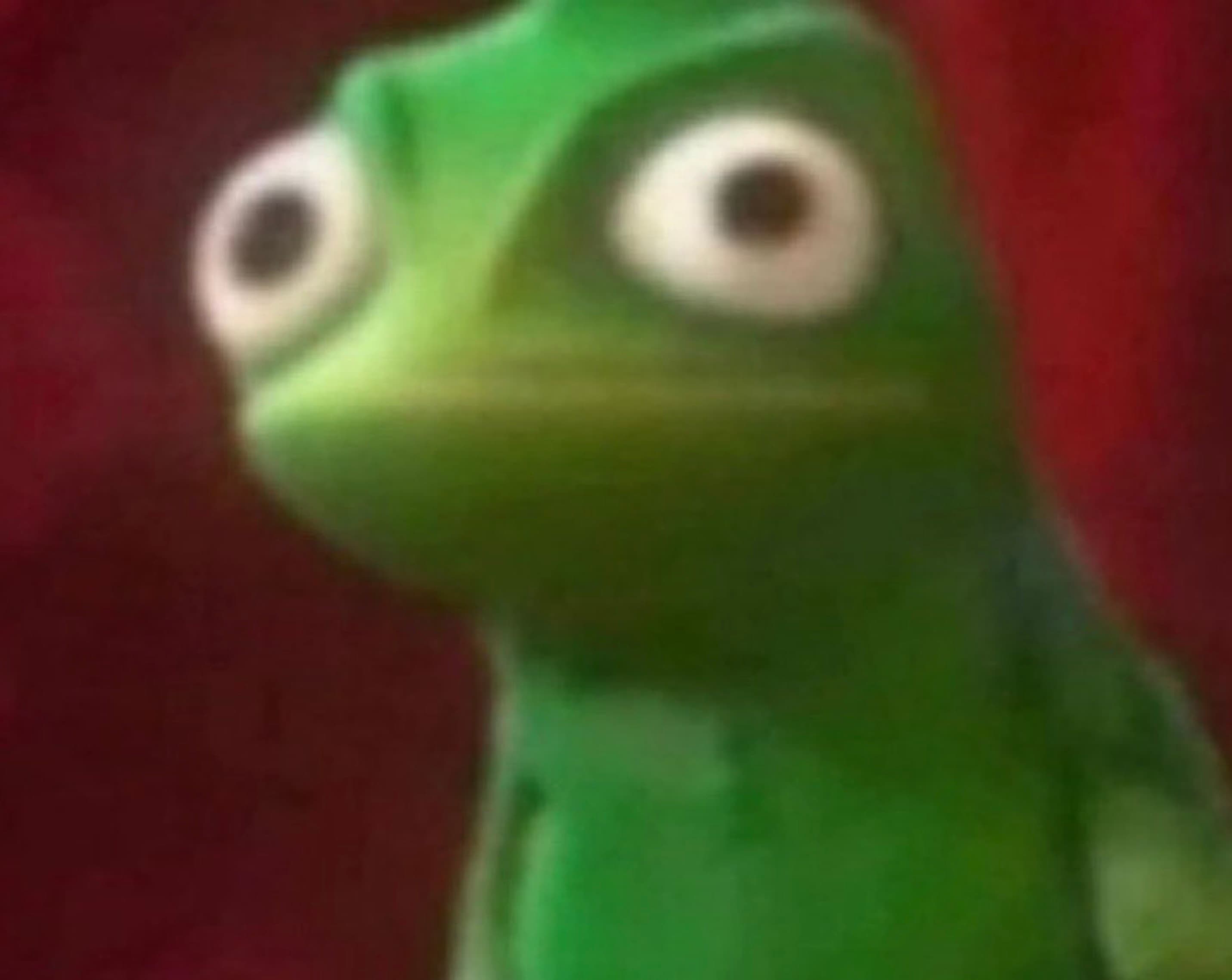 Extreme close-up of Pascal the green chameleon from Tangled with wide, shocked eyes against a red background